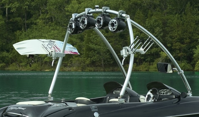 Black wakeboard boat with a Monster Tower in the middle of the water with a forest in the background.